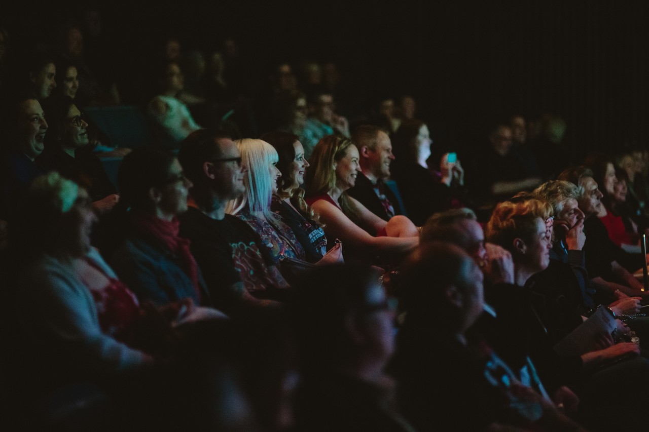 Group of people in dark theatre watching presentation