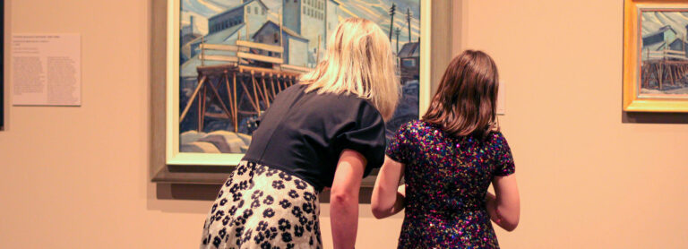 A woman and girl gaze at a painting at Glenbow. The painting includes wavy clouds, tall buildings, a wood dock and power poles in the distance.